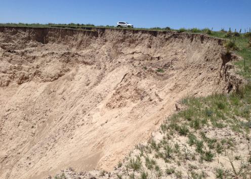 SUV parked on the rim of a large sinkhole