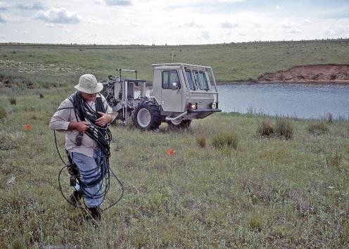 Scientists carrying cables with sinkhole in background