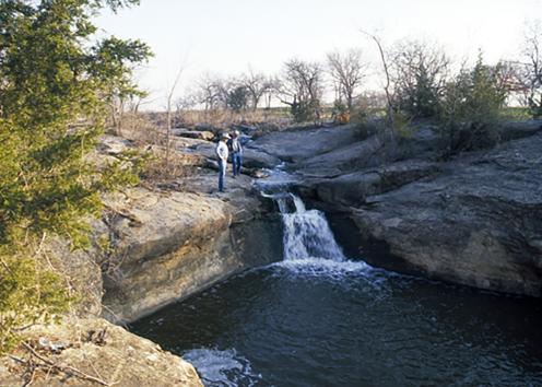 Two men standing above waterfall over rock ledge