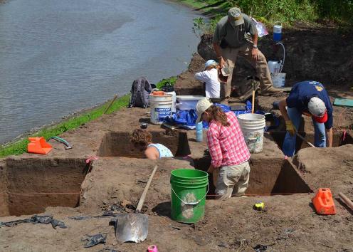 Team members excavate a series of square holes